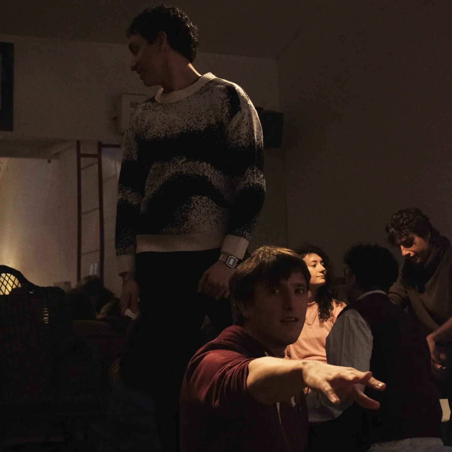 La sala en penumbra antes de la función: alguien de pie con un sweater de lana y el resto acomodándose en los sillones